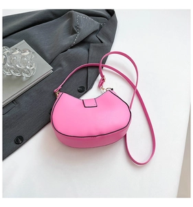 Detail of bright pink PU leather saddle bag with gold hardware and black edge paint
