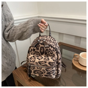 Detailansicht eines Mini-Rucksacks mit Leopardenmuster und Lederriemen auf Holztisch