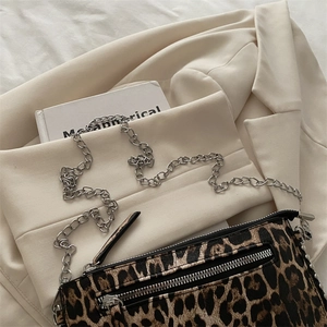 Leopard print crossbody bag with silver chain strap on cream blazer and white book