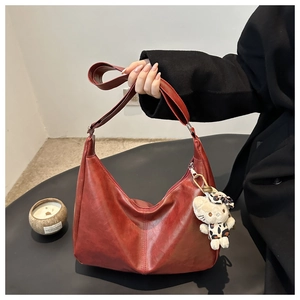 Detailed view of a burgundy retro leather hobo bag with a decorative leopard print charm