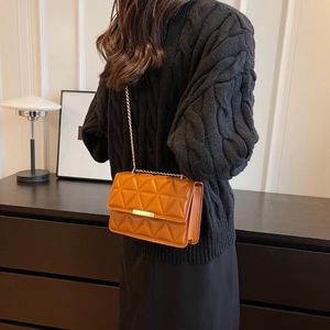 Brown quilted crossbody bag with gold chain strap shown on black sweater
