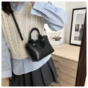 Détail du sac seau noir avec poignée nouée et finitions métalliques dorées sur la bandoulière