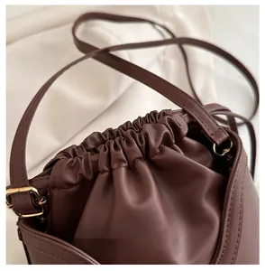 Close-up of dark brown bucket bag showing drawstring detail and smooth leather texture