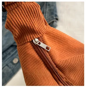 Detail of a smooth metal zipper on orange corduroy fabric of a large tote bag