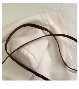 Close-up of a durable dark brown leather handle stitched onto a beige textured woven bag
