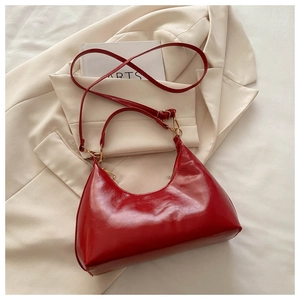 Top view of shiny red patent leather half-moon bag on beige suit blazer texture