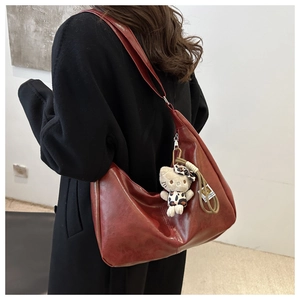 Detail of dark red vintage faux leather crossbody bag with decorative leopard plush charm