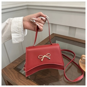 Detailed close-up of a red leather handbag featuring a golden bow-shaped metal clasp
