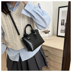 Détail d'un sac bandoulière en cuir noir avec une poignée nouée au design unique