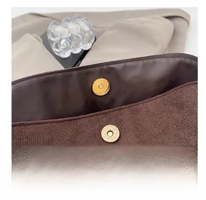 Gros plan sur le fermoir magnétique doré et la texture cuir du sac seau