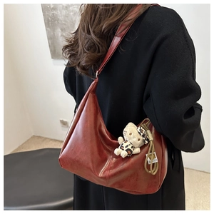 Detail of vintage burgundy leather hobo bag with natural texture and cat charm