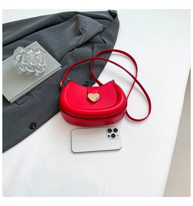 Detail view of red leather saddle bag showing size with phone and heart-shaped lock