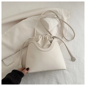 Close-up of minimalist off-white drawstring bucket bag with wave-patterned stitching