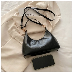 Detail view of the black crescent hobo bag next to a smartphone for size reference