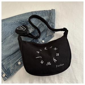 Detail of black corduroy hobo bag with white embroidery and a mini round coin purse charm
