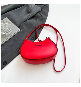Close-up of bright red hobo shoulder bag with black edge detailing on a stylish flat lay