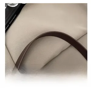 Détail de la bandoulière en cuir marron avec coutures soignées sur un sac cabas en toile