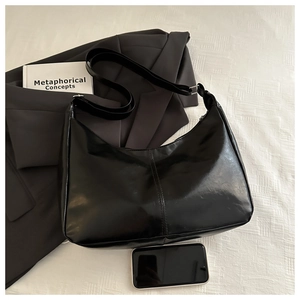 Detail of minimalist black hobo bag with adjustable wide strap and metallic buckles
