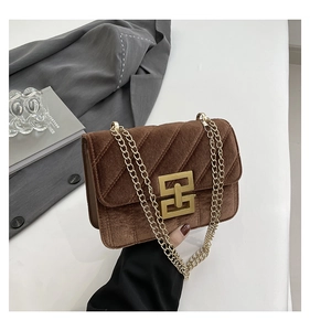 Détail du sac bandoulière en velours marron foncé avec chaîne dorée et fermoir chic