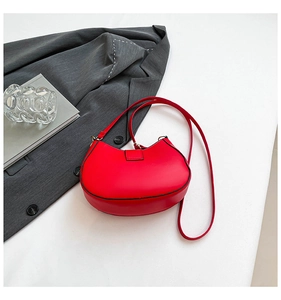 Detailed view of a bright red semi-circle hobo bag styled on a grey blazer background