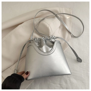 Close-up of metallic silver drawstring bucket bag with unique U-shaped stitched detailing