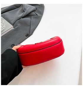 Detail of red leather saddle bag showing bottom structure, black edges, and metal hardware