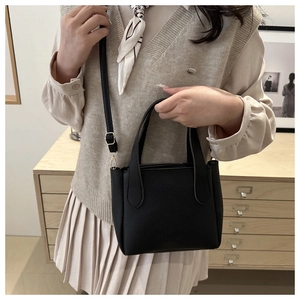 Detail of black litchi leather bucket bag with gold hardware and removable shoulder strap