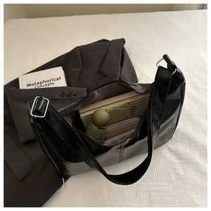 Interior view of black glossy shoulder bag showing capacity for wallet and notebook