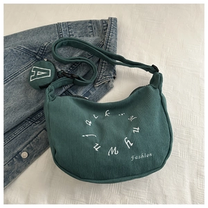 Detail of dark green corduroy crescent crossbody bag with white embroidery and round pouch