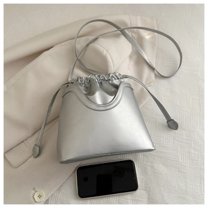 Silver metallic drawstring bucket bag shown next to a smartphone for size reference