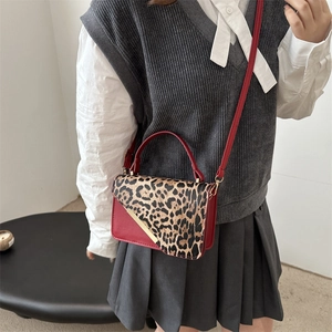 Petit sac carré rouge avec rabat léopard et barre dorée sur une tenue décontractée