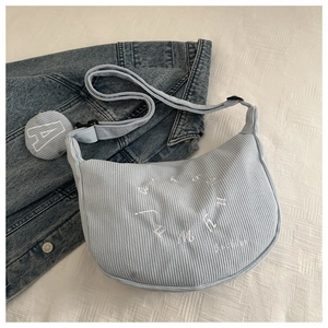 Detail of light blue corduroy shoulder bag with embroidery and matching coin purse charm
