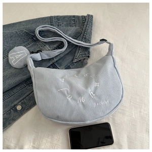 Detail of light blue corduroy crescent bag with embroidery and adjustable strap