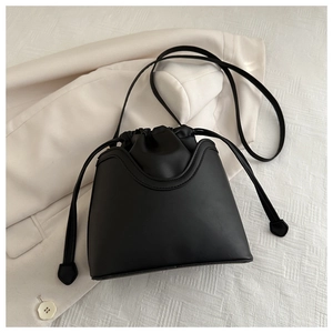 Top view of black drawstring bucket bag crafted in matte PU leather on a beige blazer