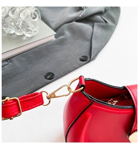 Detail of red saddle bag featuring golden metal hardware and black edge paint finish