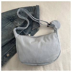 Detail of light blue corduroy crescent crossbody bag with mini pouch on denim jacket