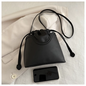 Detail of black drawstring bucket bag showing matte PU leather and its interior capacity