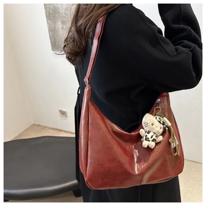 Detail of burgundy crescent shoulder bag with glossy PU leather and leopard plush charm
