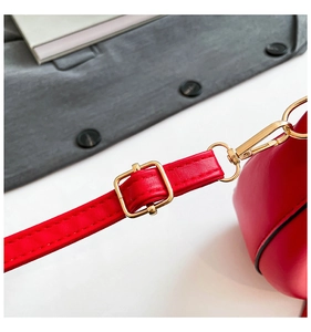 Close-up of red leather shoulder strap with polished gold hardware and precision stitching