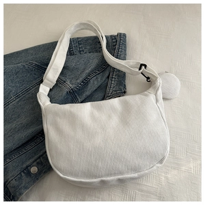 Detail of white corduroy crescent bag with textured stripes and round coin purse attachment