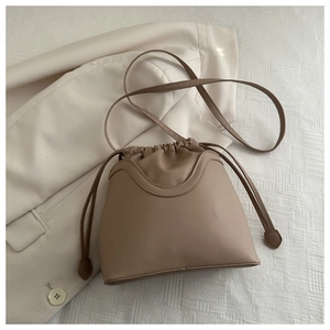 Detail of taupe drawstring bucket bag with U-shaped stitching on beige blazer