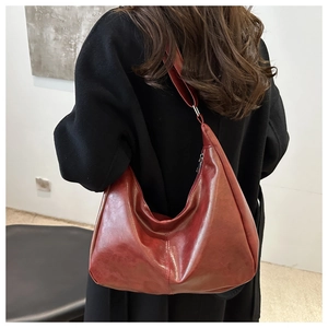 Large vintage burgundy faux leather hobo tote bag worn by model in black coat