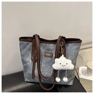 Close-up of stone-washed canvas tote with brown leather straps and cloud plush charm