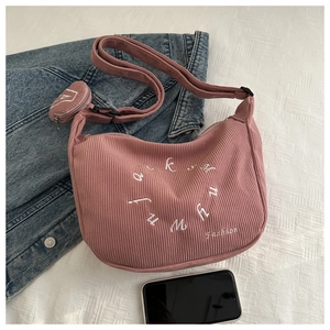 Pink corduroy crescent shoulder bag featuring embroidery detail and a small round coin purse