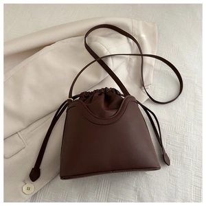 Detailed view of deep brown leather bucket bag with drawstring closure and U-shaped stitching