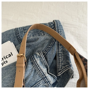 Détail de la bandoulière réglable en cuir marron avec boucle dorée sur sac à imprimé léopard