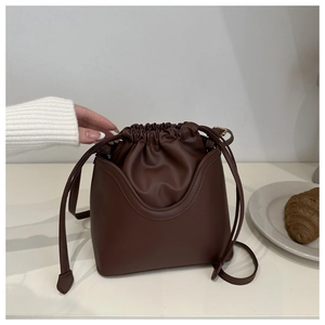 Detail of vintage coffee brown bucket bag with drawstring closure in a minimalist setting