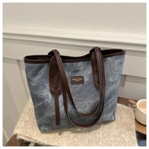 Detail of blue marble denim tote bag with brown leather handles and classic leather patch