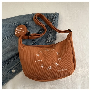 Detailed close-up of brown corduroy crescent bag with embroidery and round coin purse