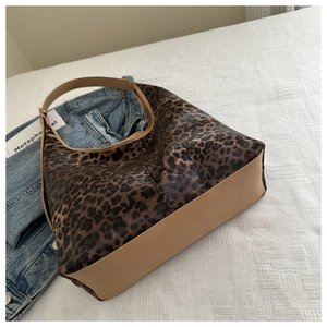 Détail du sac cabas à imprimé léopard avec bordure en cuir kaki sur fond textile blanc